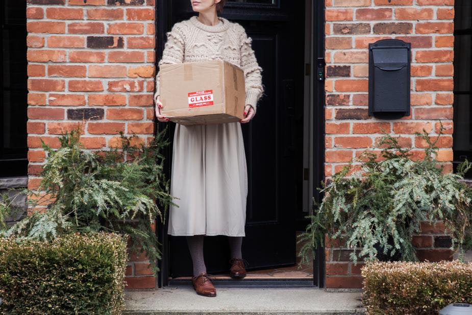 Una mujer recoge un paquete de su puerta