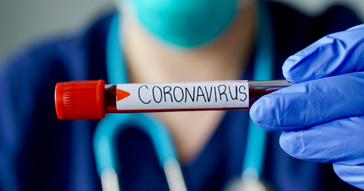 Nurse wearing respirator mask holding a positive blood test result for Coronavirus.